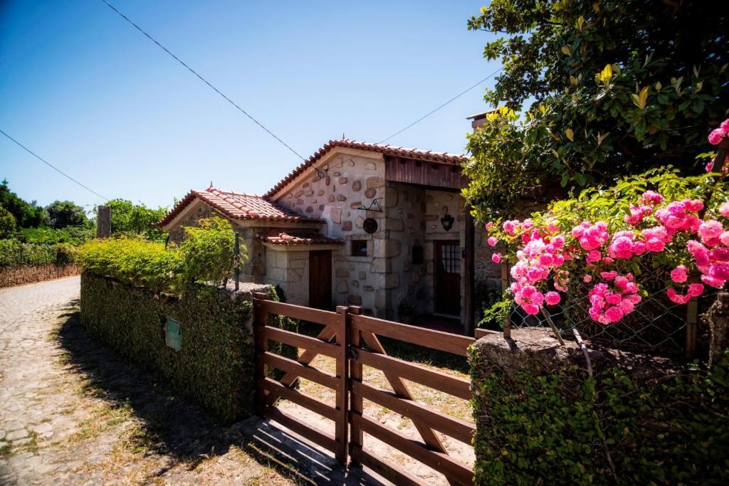 a small house with a fence and pink flowers at Casa do Tamanqueiro in Ponte de Lima