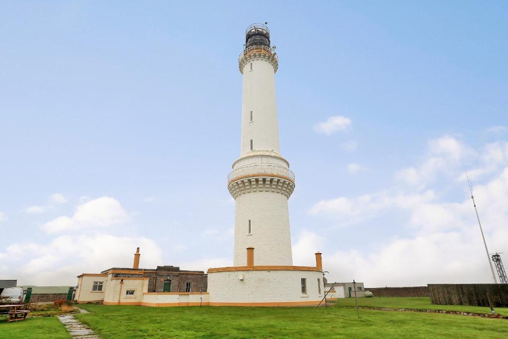 a lighthouse on top of a grass field at Aberdeen Lighthouse Cottages - coastal, dolphins in Aberdeen