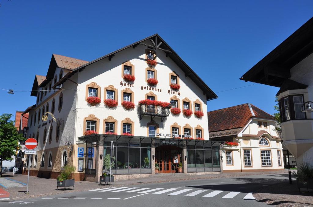 a large white building with red flowers on the windows at Hotel Goldener Hirsch in Reutte