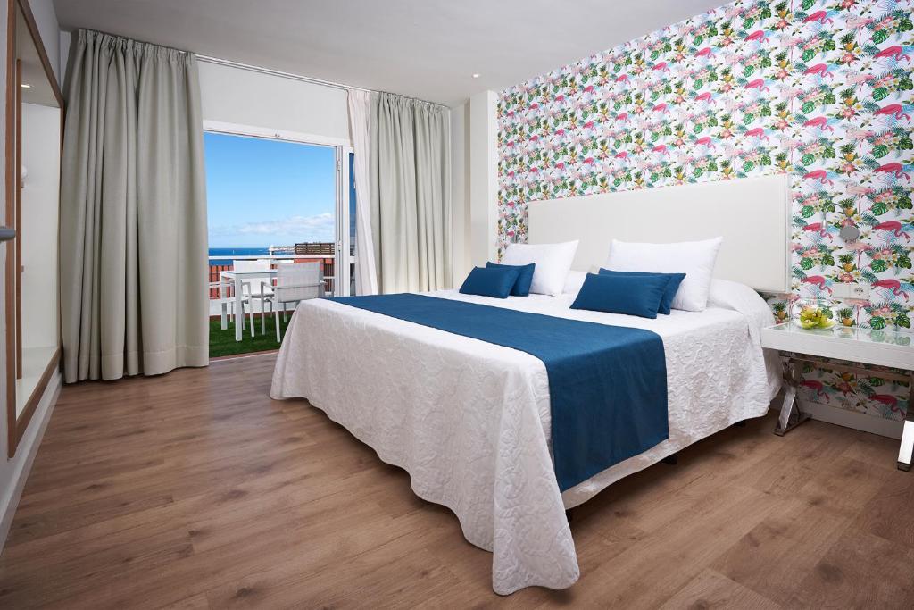a bedroom with a large bed with a blue blanket at Flamingo Beach Mate in Adeje