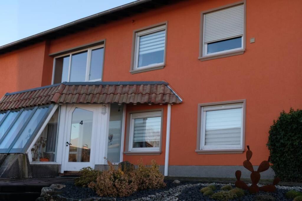 uma casa laranja com janelas brancas e um alpendre em Ferienwohnung Vicus - am Fuße des Schaumberges em Tholey