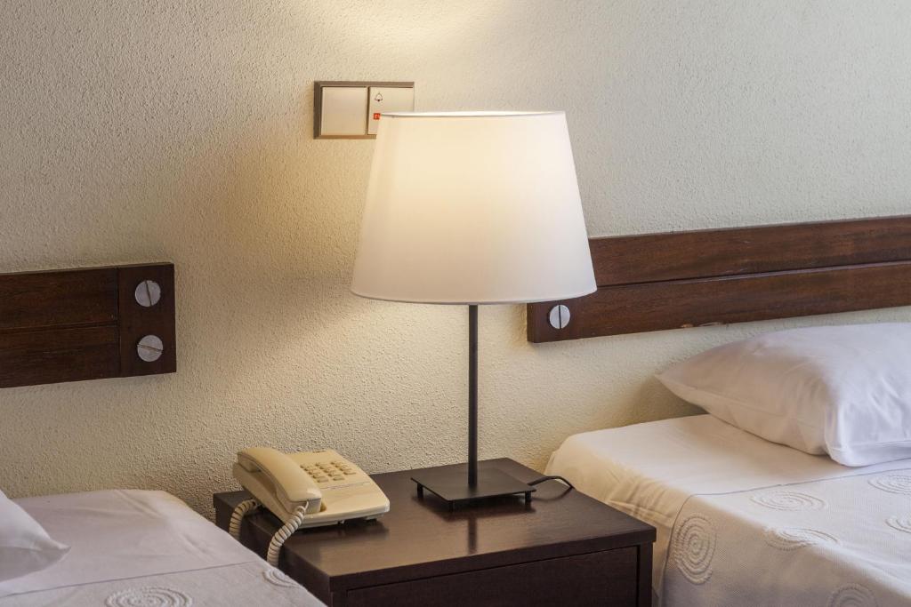 a lamp on a table in a hotel room with a phone at Hotel Sete Cidades in Ponta Delgada