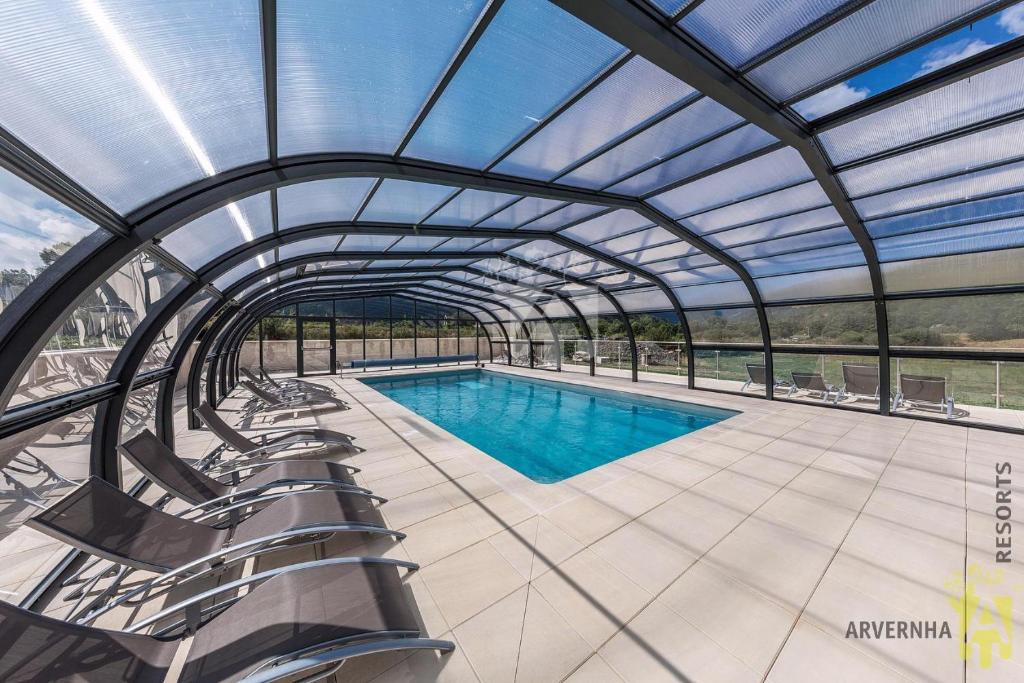 a swimming pool with a pergola and chairs around it at Chalets de Fougerousse in Chambon-sur-Lac