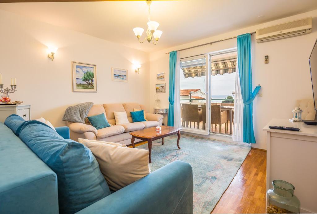ein Wohnzimmer mit einem blauen Sofa und einem Tisch in der Unterkunft Apartments Royal Residence in Baška Voda