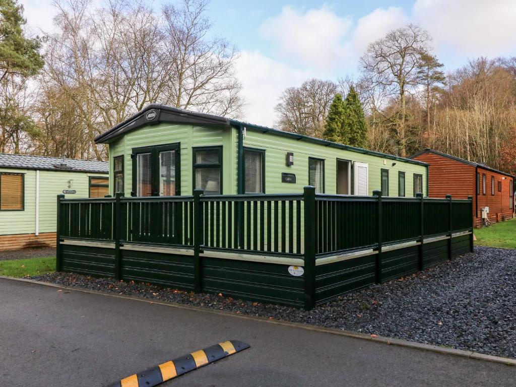 a green tiny house with a black fence at Calgarth Lodge in Windermere