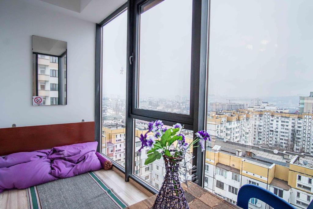 a room with a vase with purple flowers in front of a window at Sky House Panorama MAIN STREET Chisinau in Chişinău