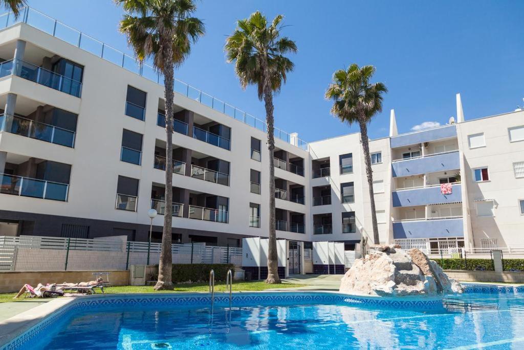 a swimming pool in front of a building with palm trees at Apartament Puerto Romano, La Mata, close to the beach plus parking space in the underground garage in La Mata