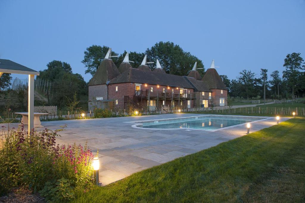a large house with a swimming pool in front of it at Goudhurst Oast by Bloom Stays in Goudhurst