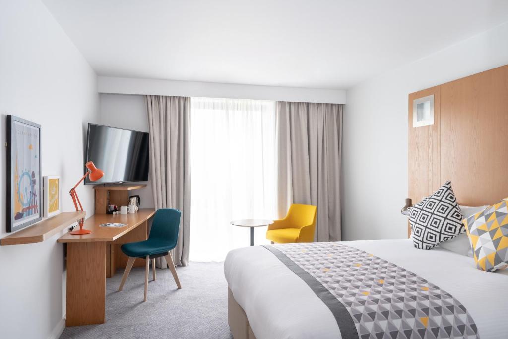 a hotel room with a bed and a desk at Holiday Inn Bournemouth by IHG in Bournemouth