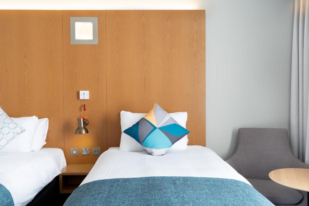 a bedroom with a bed with a blue and white pillow at Holiday Inn Bournemouth by IHG in Bournemouth