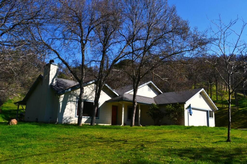 una casa blanca en un campo verde con árboles en Blue Jay Paradise, en Three Rivers