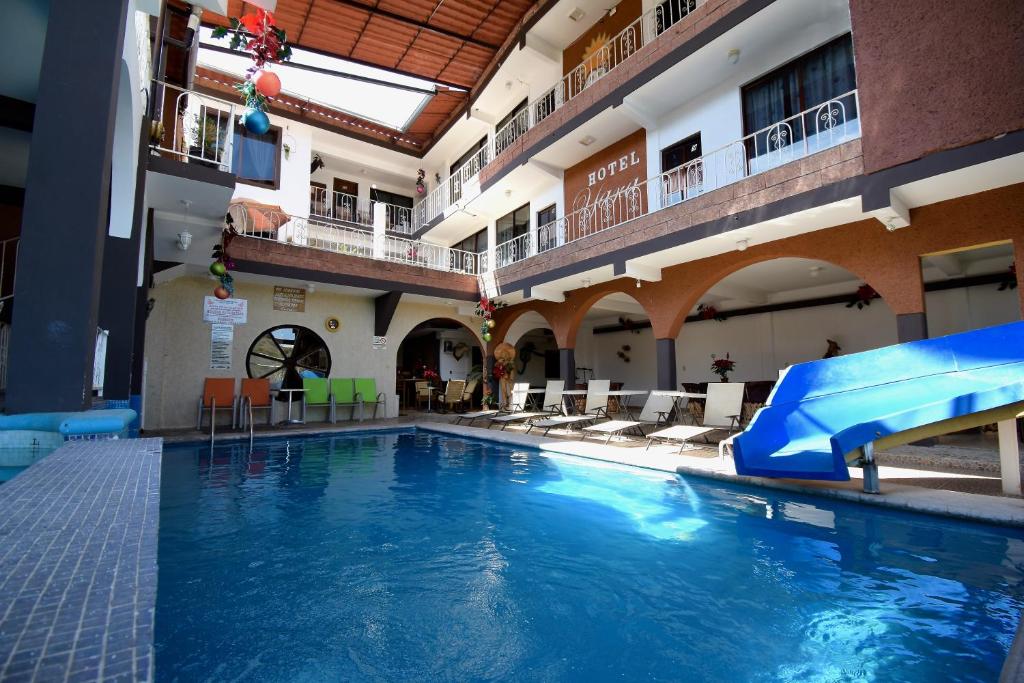a large swimming pool with a slide in a building at Hotel Yara in Ixtapan de la Sal