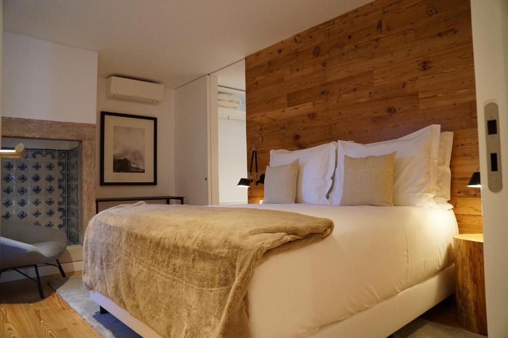 una camera da letto con un grande letto bianco e una parete in legno di Flora Baixa Apartments a Lisbona