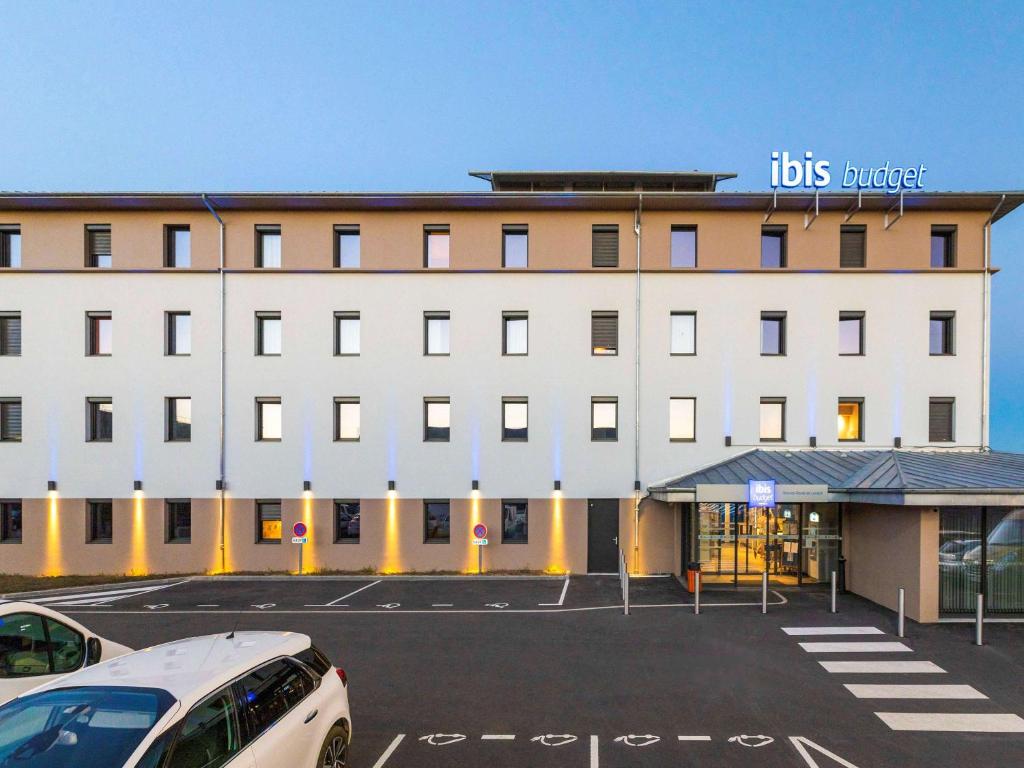 een groot wit gebouw met een parkeerplaats ervoor bij ibis budget Rennes Rte Lorient in Rennes