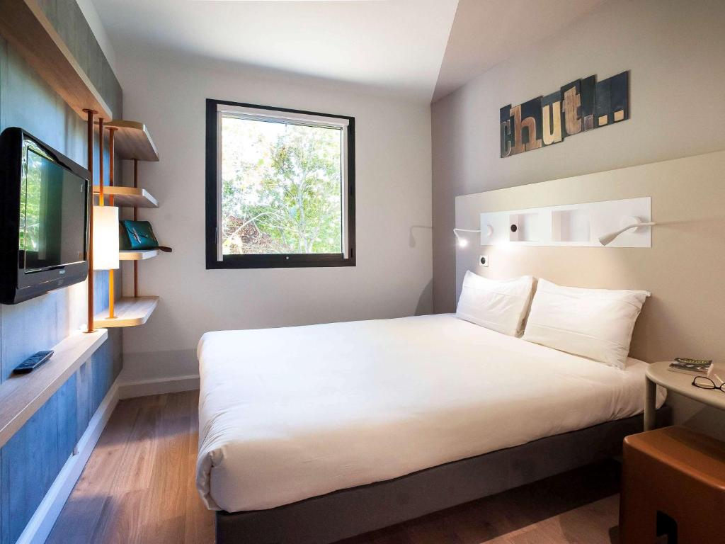 エソーム・シュル・マルヌにあるibis budget Château-Thierryの大型ベッドとテレビが備わるホテルルームです。