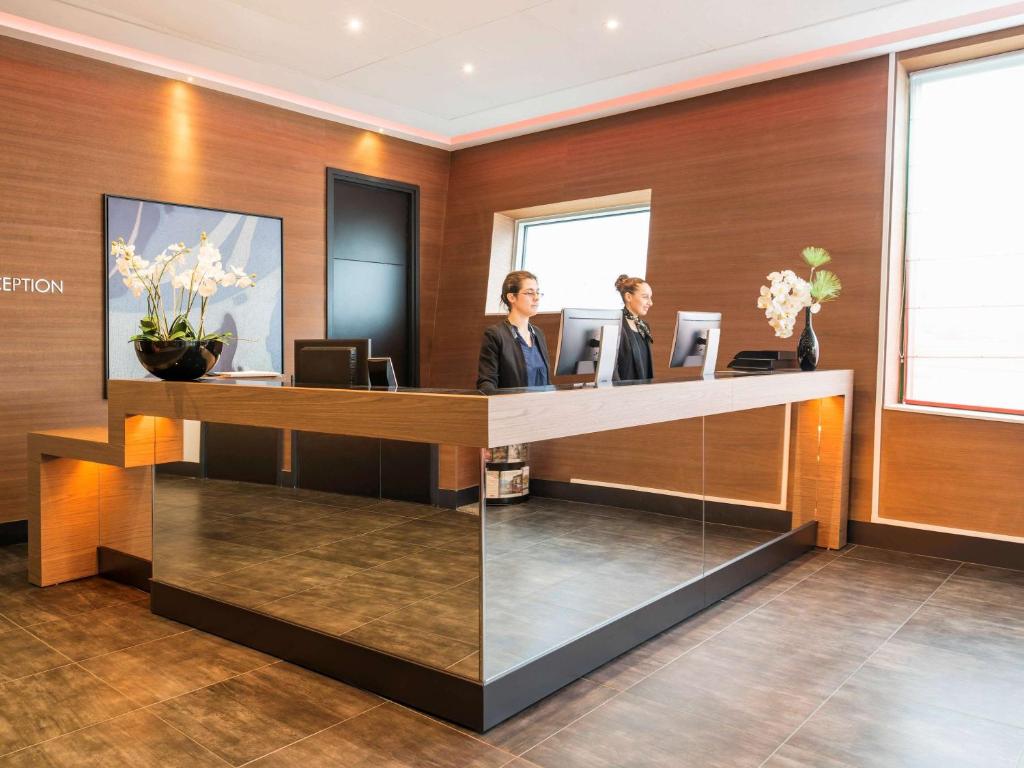 two women standing at a reception desk at Adagio Paris 19ème Cité de la Musique in Paris