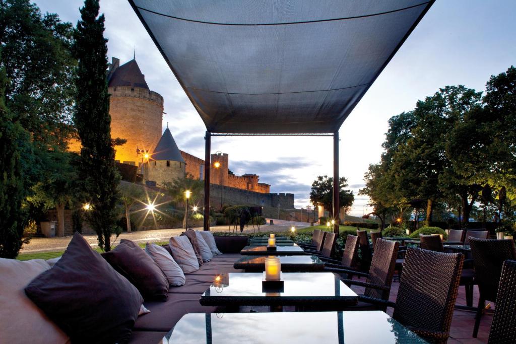 une terrasse avec des tables et des chaises en face d'un château dans l'établissement Hôtel du Château & Spa - Teritoria, à Carcassonne