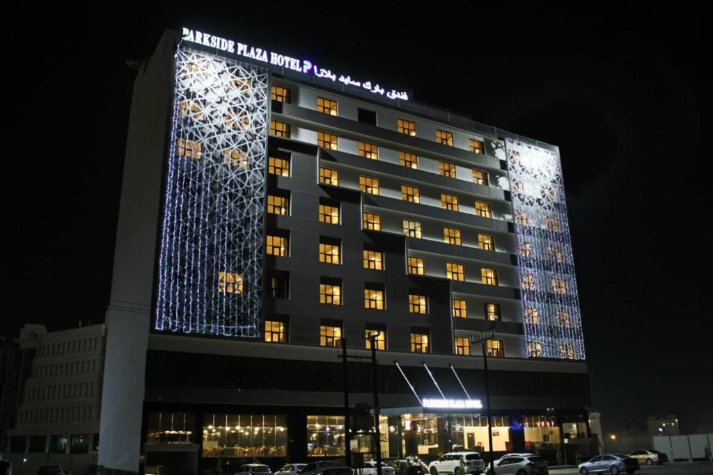 a hotel building with a lit up facade at night at Parkside Plaza Muscat in Muscat