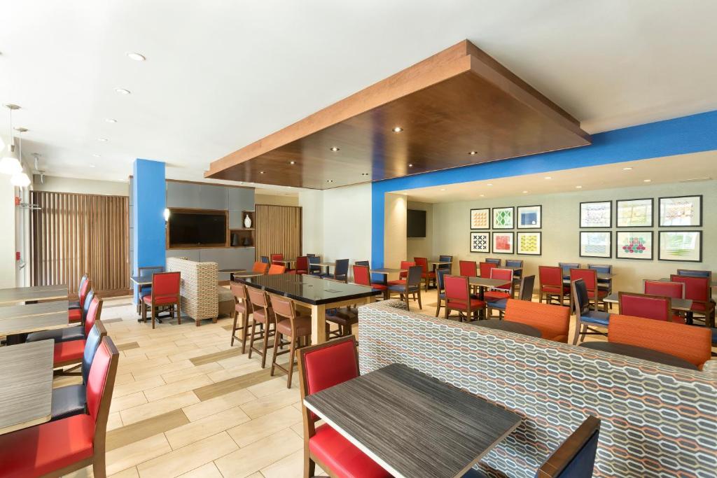 a dining room with tables and chairs in a restaurant at Holiday Inn Express & Suites S Lake Buena Vista by IHG in Kissimmee