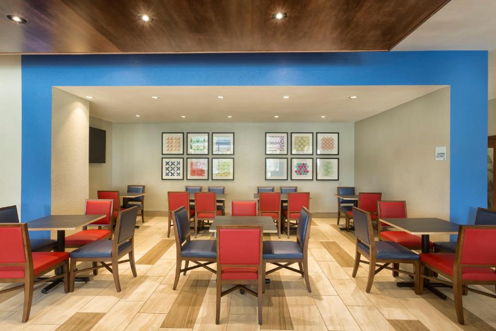 a dining room with tables and red chairs at Holiday Inn Express & Suites S Lake Buena Vista by IHG in Kissimmee
