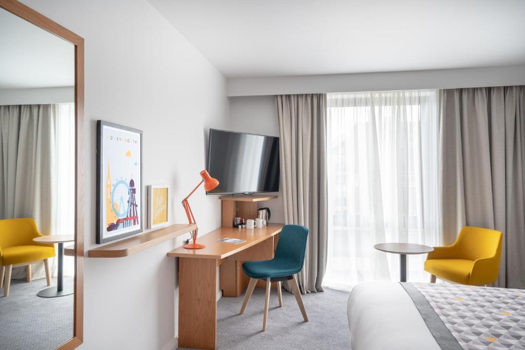 a hotel room with a bed and a desk and a tv at Holiday Inn Bournemouth by IHG in Bournemouth