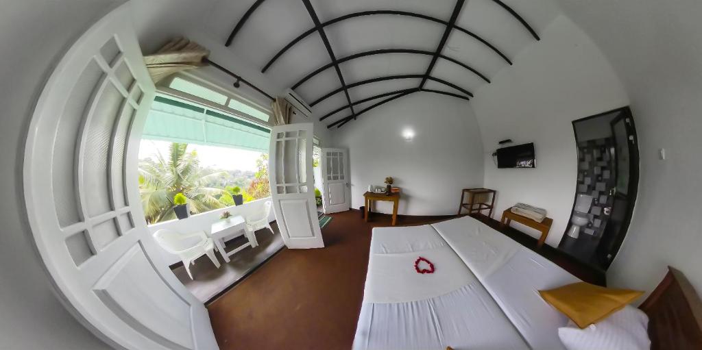 a room with a large white room with a large window at Kandy Mountain Cottage in Kandy