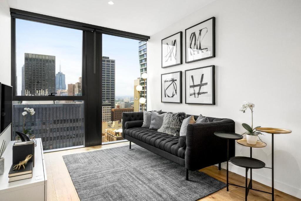 a living room with a couch and a large window at Luxuria Apartments - Collins House in Melbourne