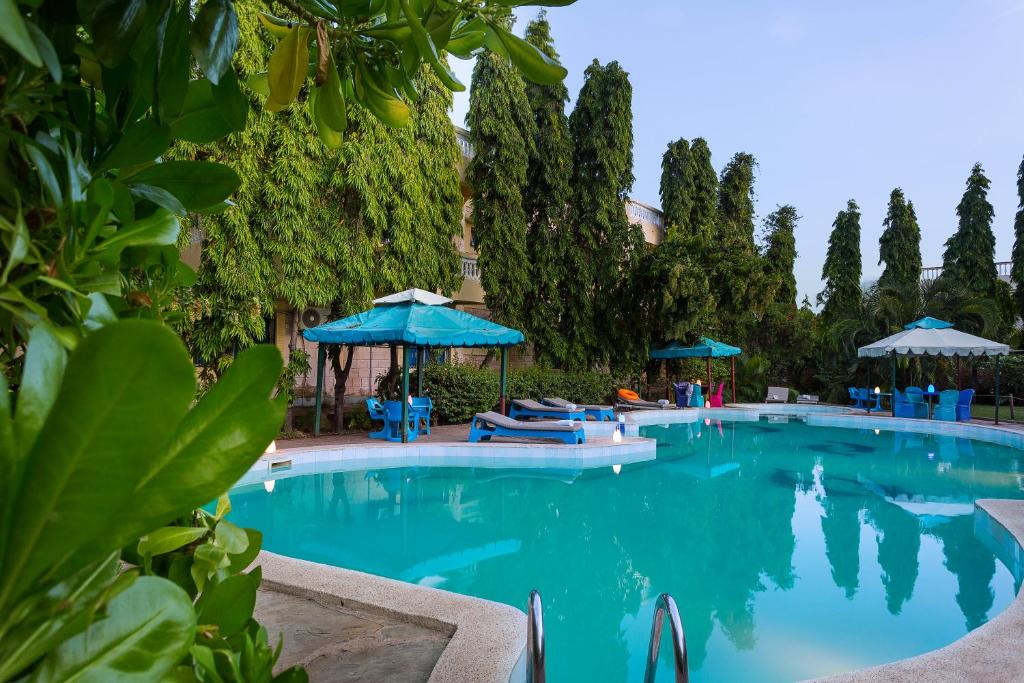 una gran piscina con sillas y sombrillas azules en Jacyjoka Apartments Nyali en Mombasa