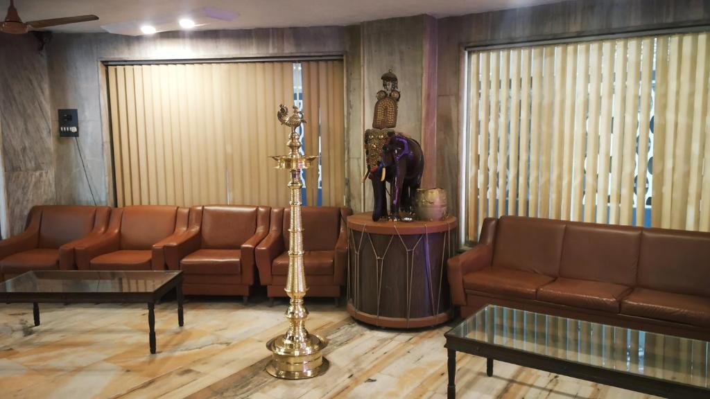 a waiting room with couches and chairs and a statue at Hotel Elite International in Trichūr