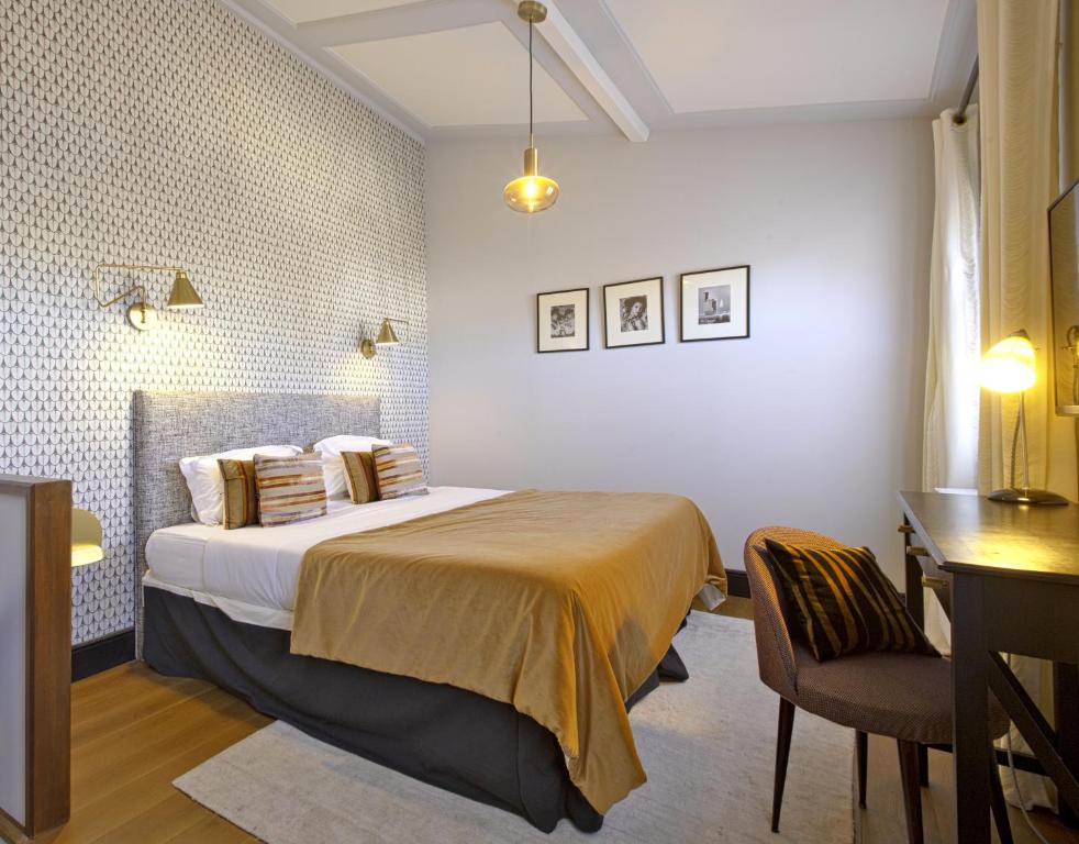 Habitación de hotel con cama, escritorio y mesa. en Villa Segur, en Burdeos