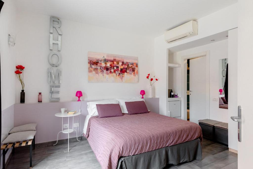 ローマにあるRhome Accomodationの白いベッドルーム(ピンクベッド1台、テーブル付)