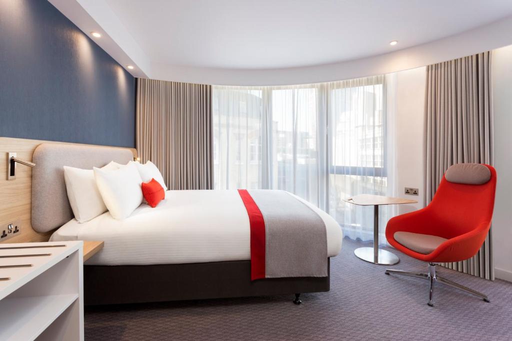 een hotelkamer met een bed en een rode stoel bij Holiday Inn Express Southwark by IHG in Londen