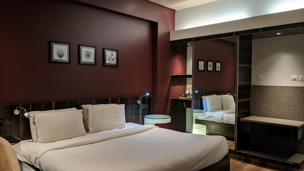 ein Hotelzimmer mit einem großen Bett und einem Spiegel in der Unterkunft Hotel Sankam Residency in Belgaum