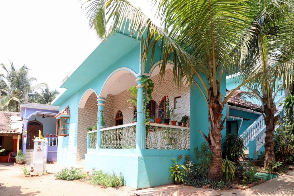 un edificio azul con una palmera delante de él en Fraddie Guest House, en Calangute
