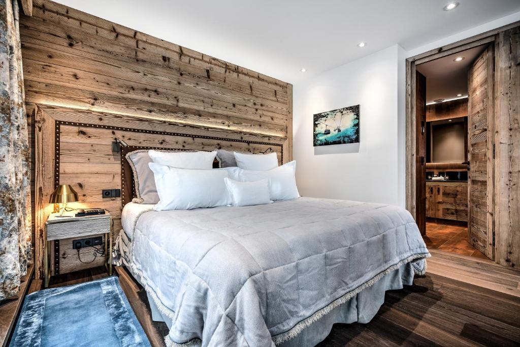 a bedroom with a large bed and a wooden wall at Hôtel La Sivolière in Courchevel