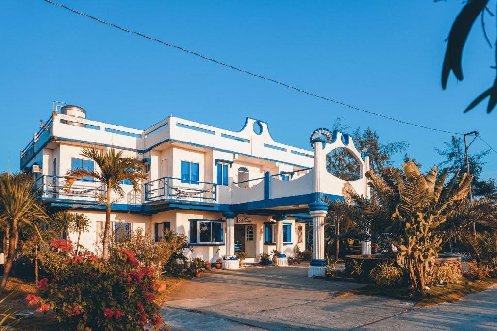 una gran casa blanca con palmeras delante en Club Monet Beachfront Resort by Cocotel, en Zambales