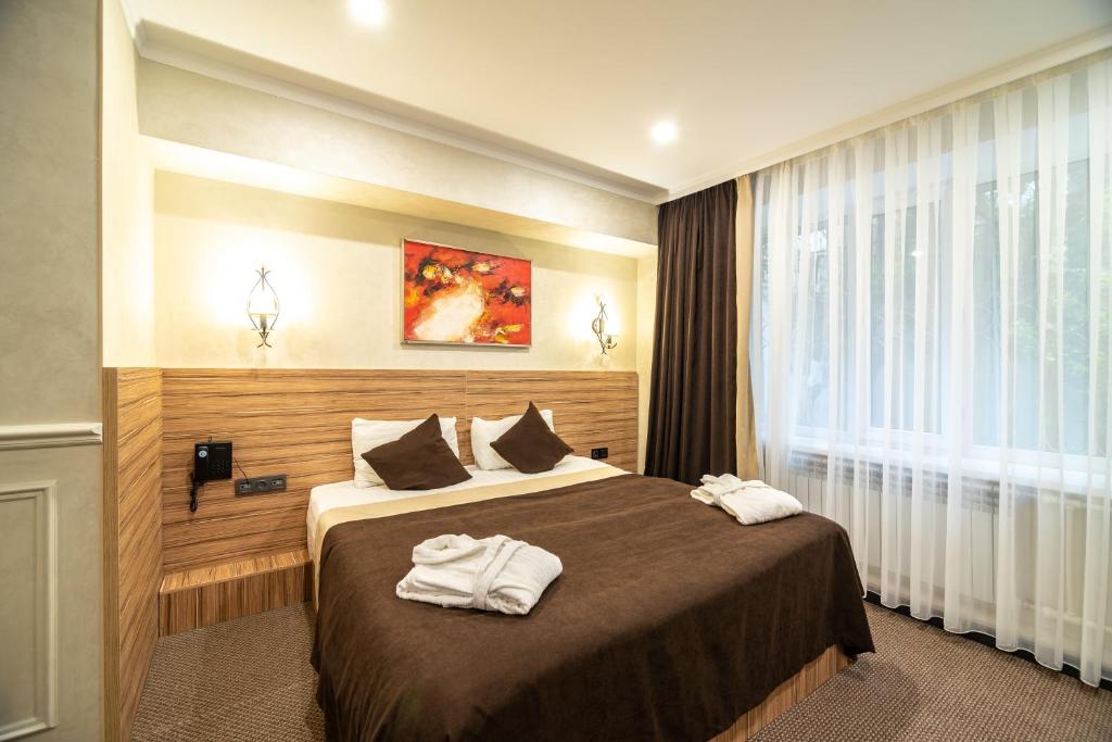 Mildom City Hotel في ألماتي: غرفة فندق عليها سرير وفوط
