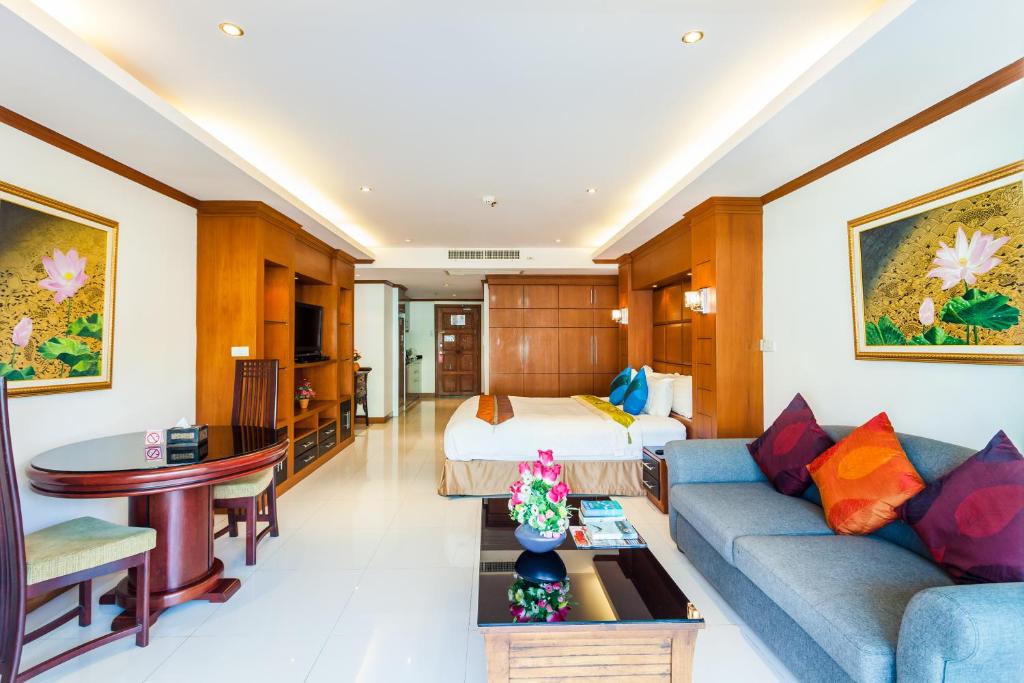 Habitación de hotel con cama y sofá azul en Tara Court Hotel, en Pattaya South