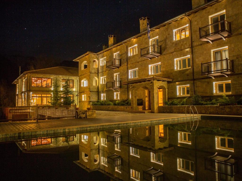 un edificio con su reflejo en el agua por la noche en Styga Mountain Resort en Zarouhla