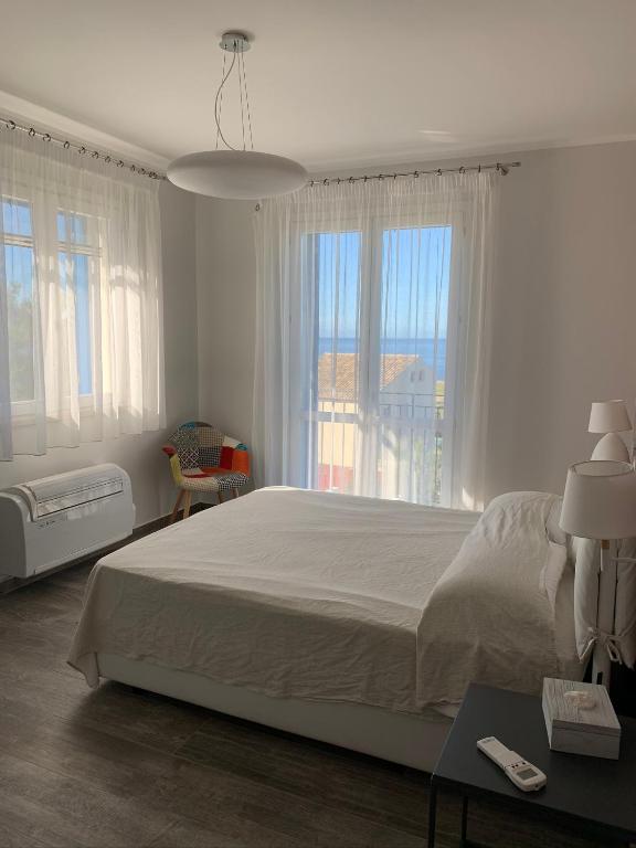 biała sypialnia z dużym łóżkiem i oknami w obiekcie casa Cuffa w mieście San Vito lo Capo