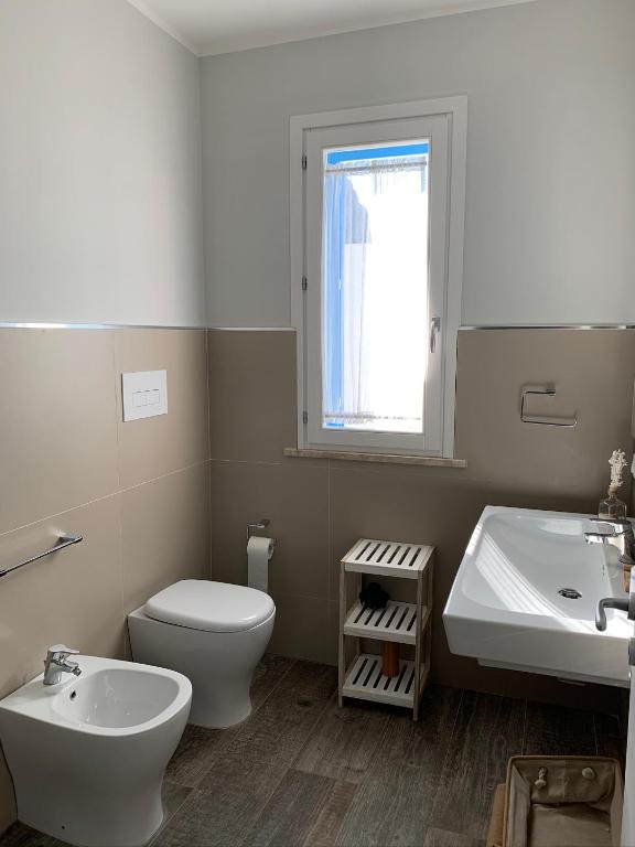 łazienka z toaletą, umywalką i oknem w obiekcie casa Cuffa w mieście San Vito lo Capo