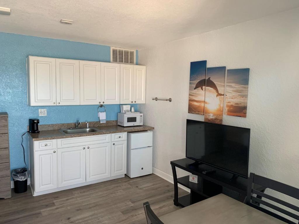 a kitchen with white cabinets and a sink and a microwave at Sandalwood Beach Resort in St. Pete Beach