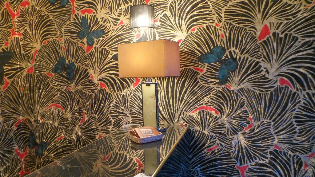 a lamp on a table in a room with a wallpaper at Hotel Relais Du Postillon in Antibes