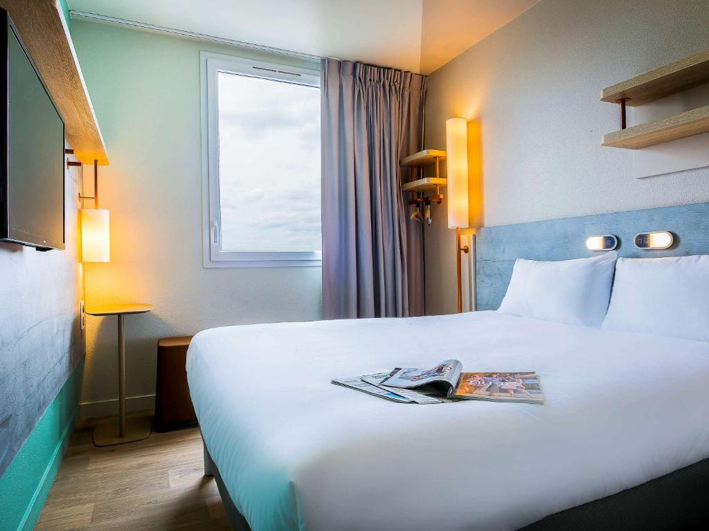una habitación de hotel con una cama con una revista. en ibis budget Paris Gennevilliers, en Gennevilliers