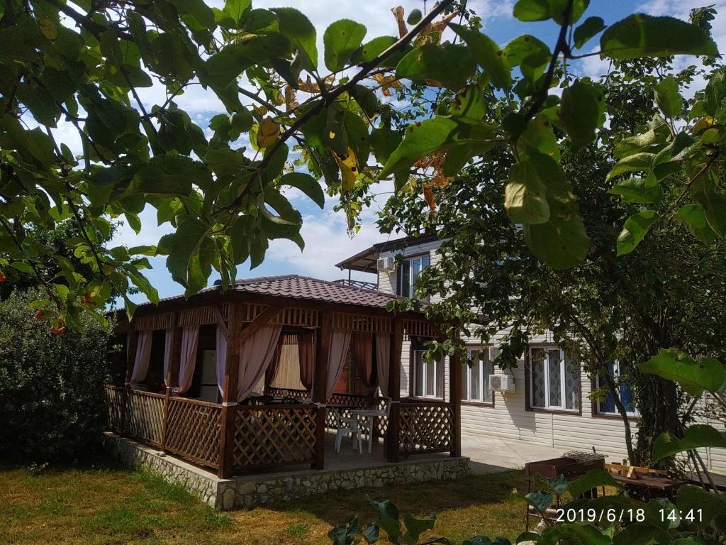 una casa con un porche y un árbol en Бархат en Tsandrypsh