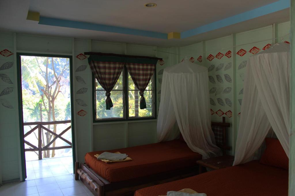 een slaapkamer met 2 bedden en een raam met gordijnen bij Chill Out Bar and Bungalows in Tonsai Beach