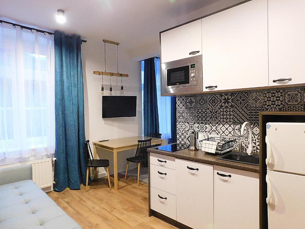 une cuisine avec des placards blancs et une table avec un bureau dans l'établissement Apartament BAJ No.2, à Toruń