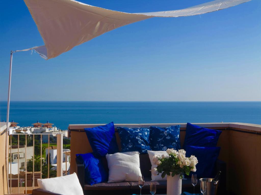 un sofá con almohadas azules en un balcón con vistas al océano en Penthouse Aloha4you, en Mojácar
