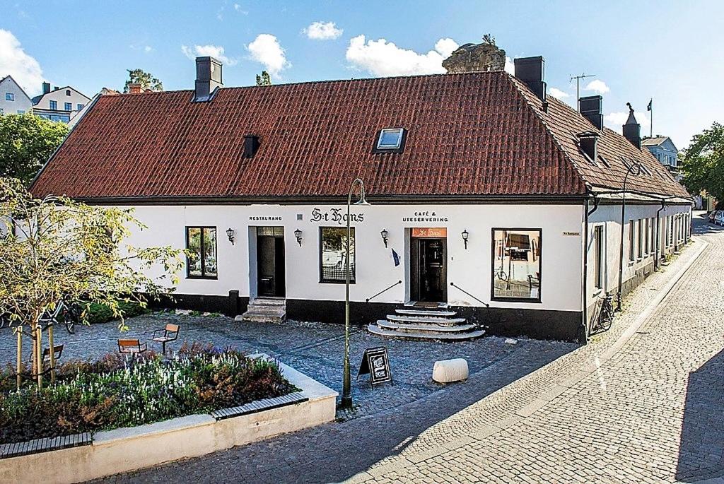 un bâtiment blanc avec un toit rouge dans une rue dans l'établissement Villa S:t Hans, à Visby