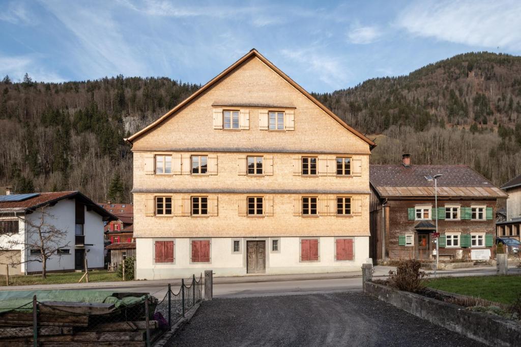 un gran edificio en un pueblo con una montaña en Ferienwohnung Gertrud, en Bezau